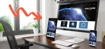 A modern workspace showcasing landing page optimization best practices features a desktop computer, tablet, and smartphone displaying a digital network theme. A red arrow points to a potted plant by the window. The setup is on a wooden desk with keyboard and mouse.